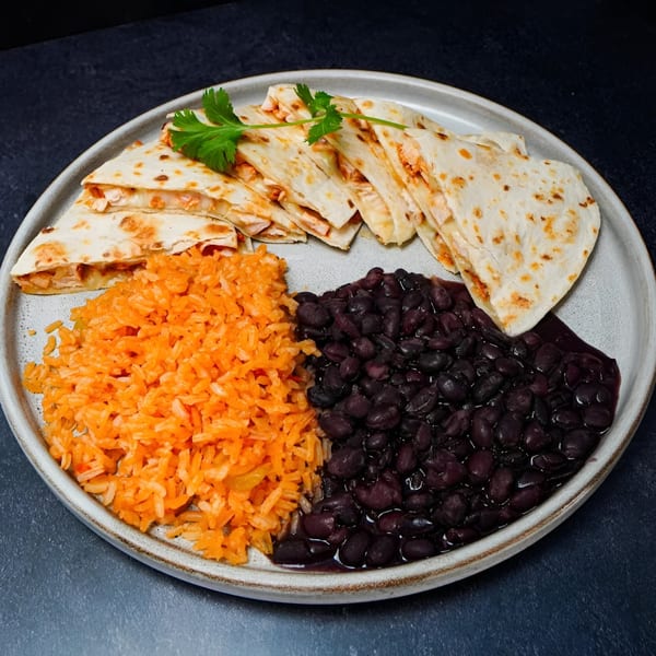 Cancun Express quesadillas with cilantro, orange rice, and black beans on a white plate.